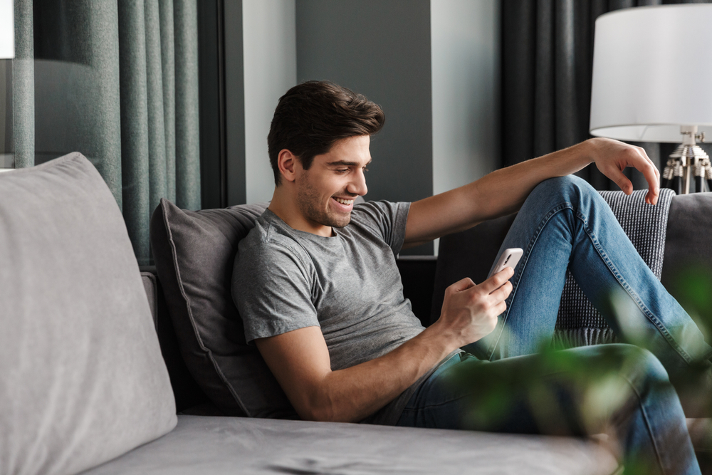 happy attractive man smiling texting